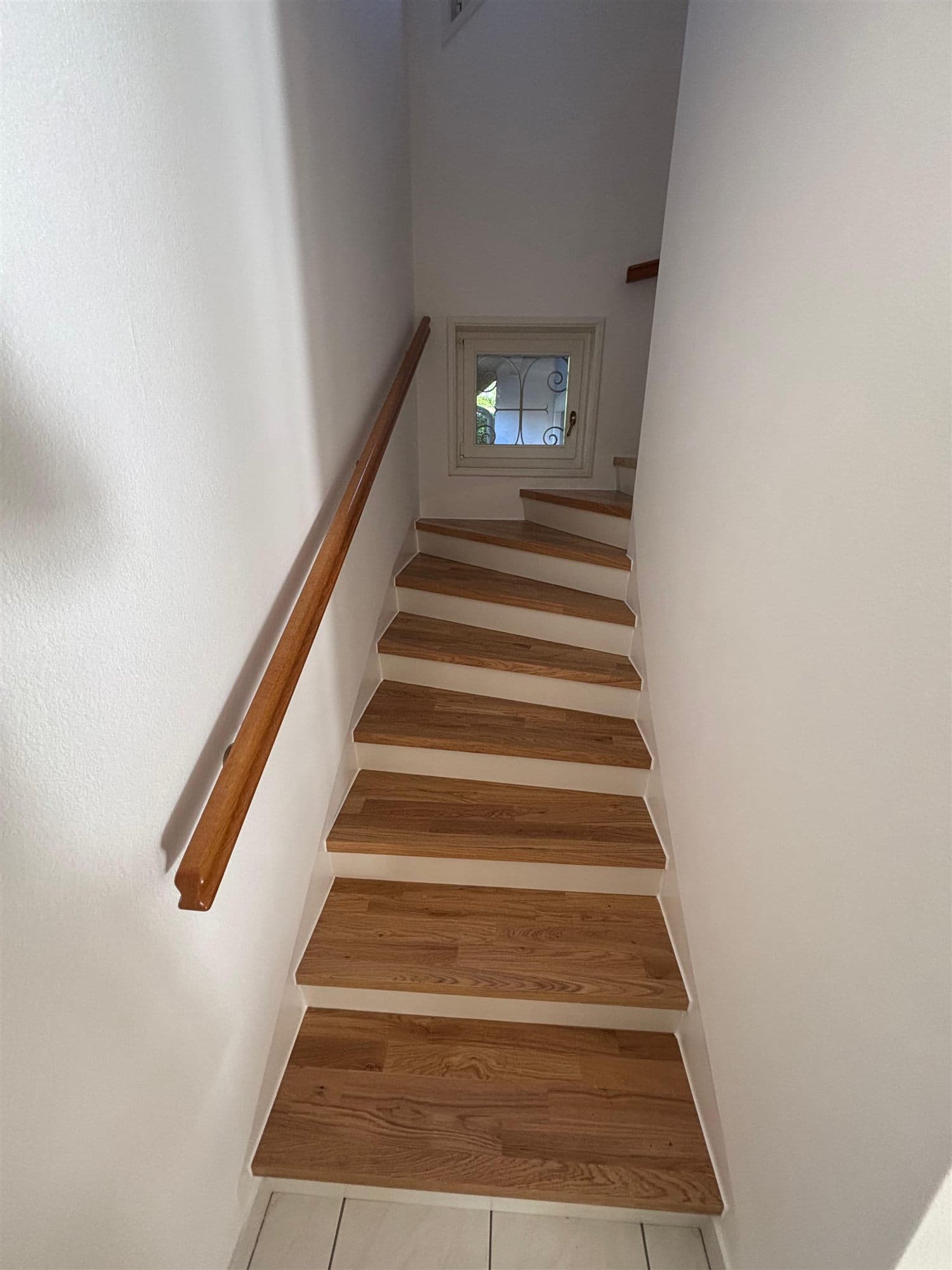 Le même escalier terminé : limons et contremarches peints en blanc, marches et main courante en bois