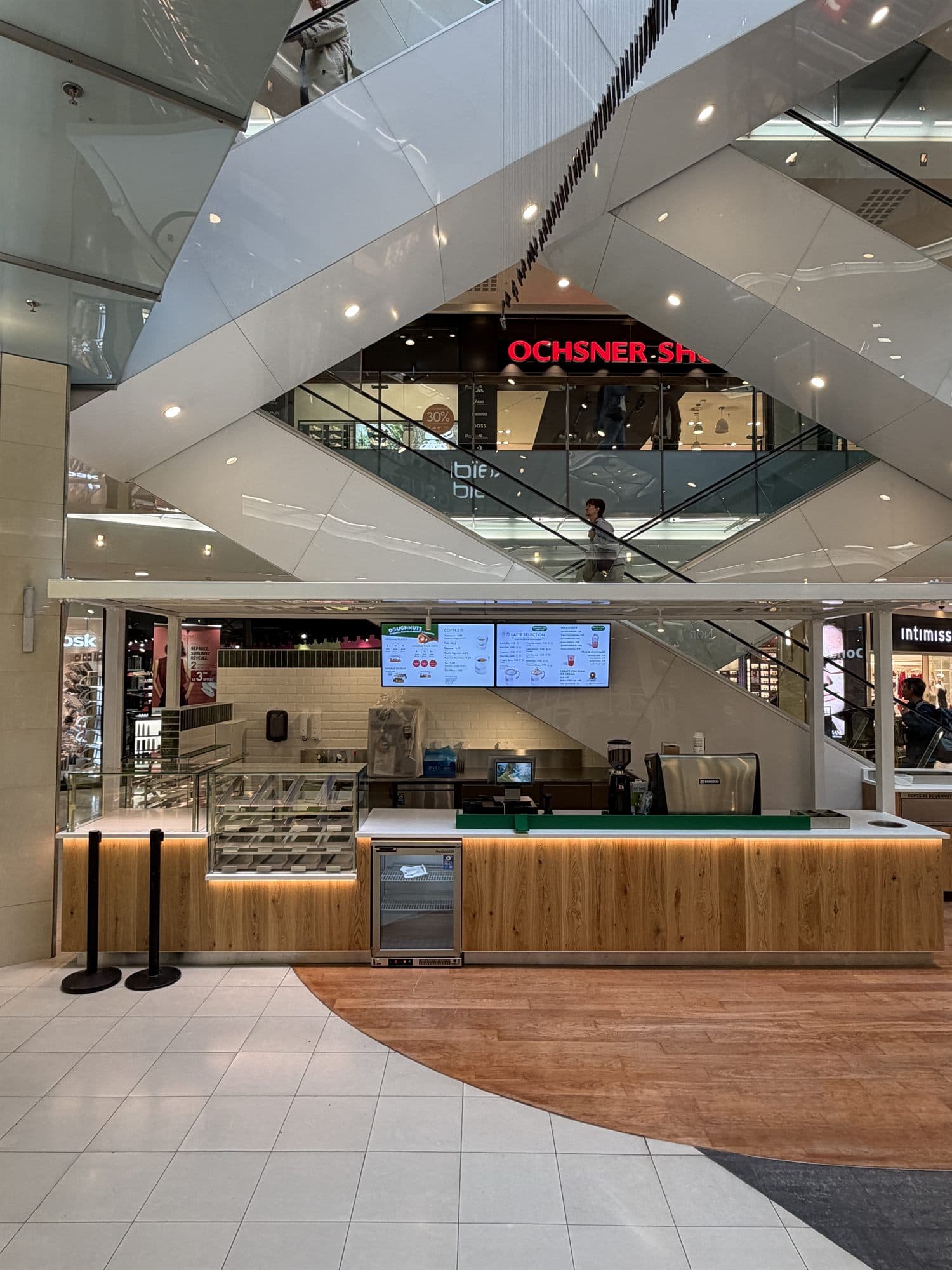 Le stand Krispy Kreme terminé : comptoir en bois, éclairage intégré et écrans de menu