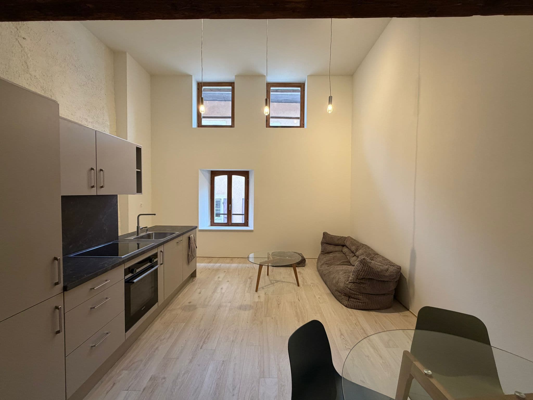 Le même séjour après rénovation : murs lissés et peints, cuisine équipée et parquet clair